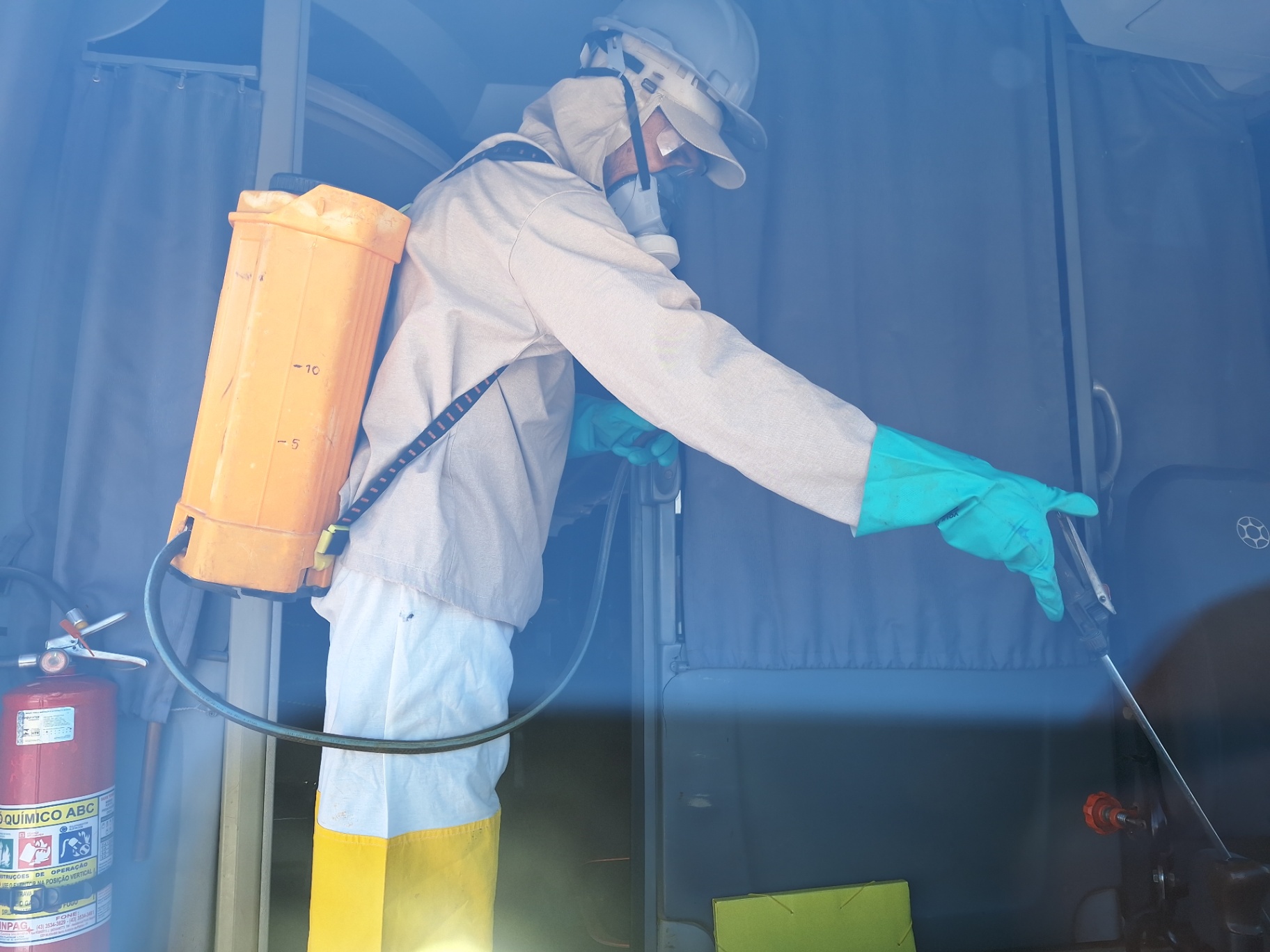Técnico uniformizado aplicando desinsetização em veículo